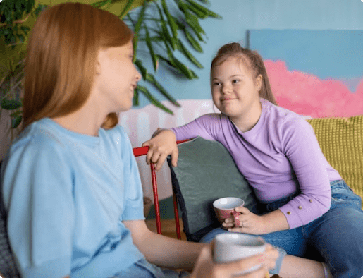 Two young girls conversing while drinking water. 