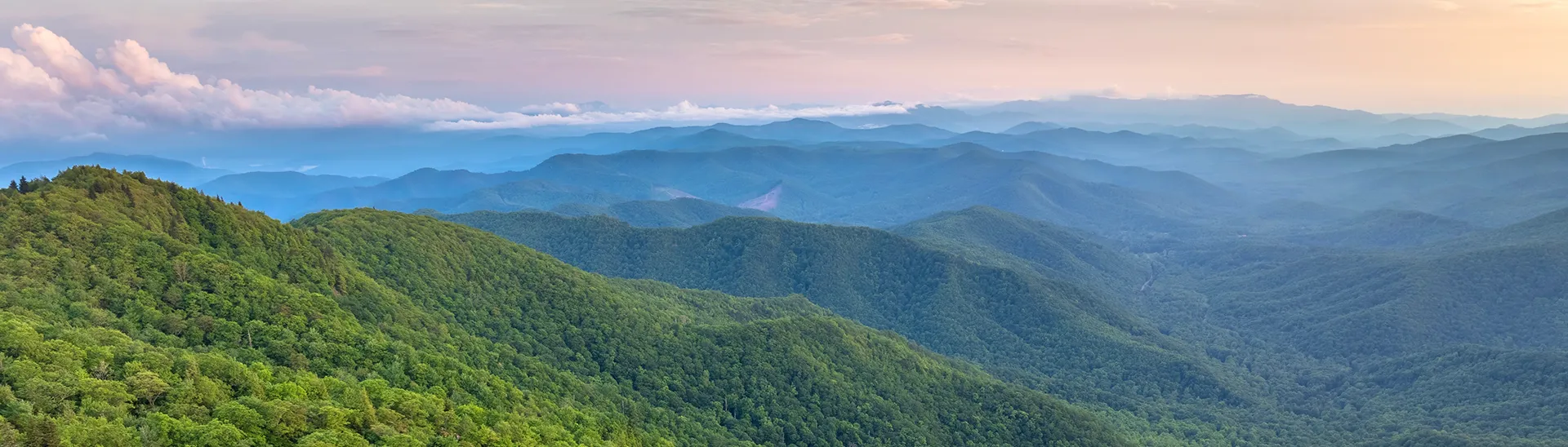 A mountain range at sunset as the sky is changing colors from blue to pink.